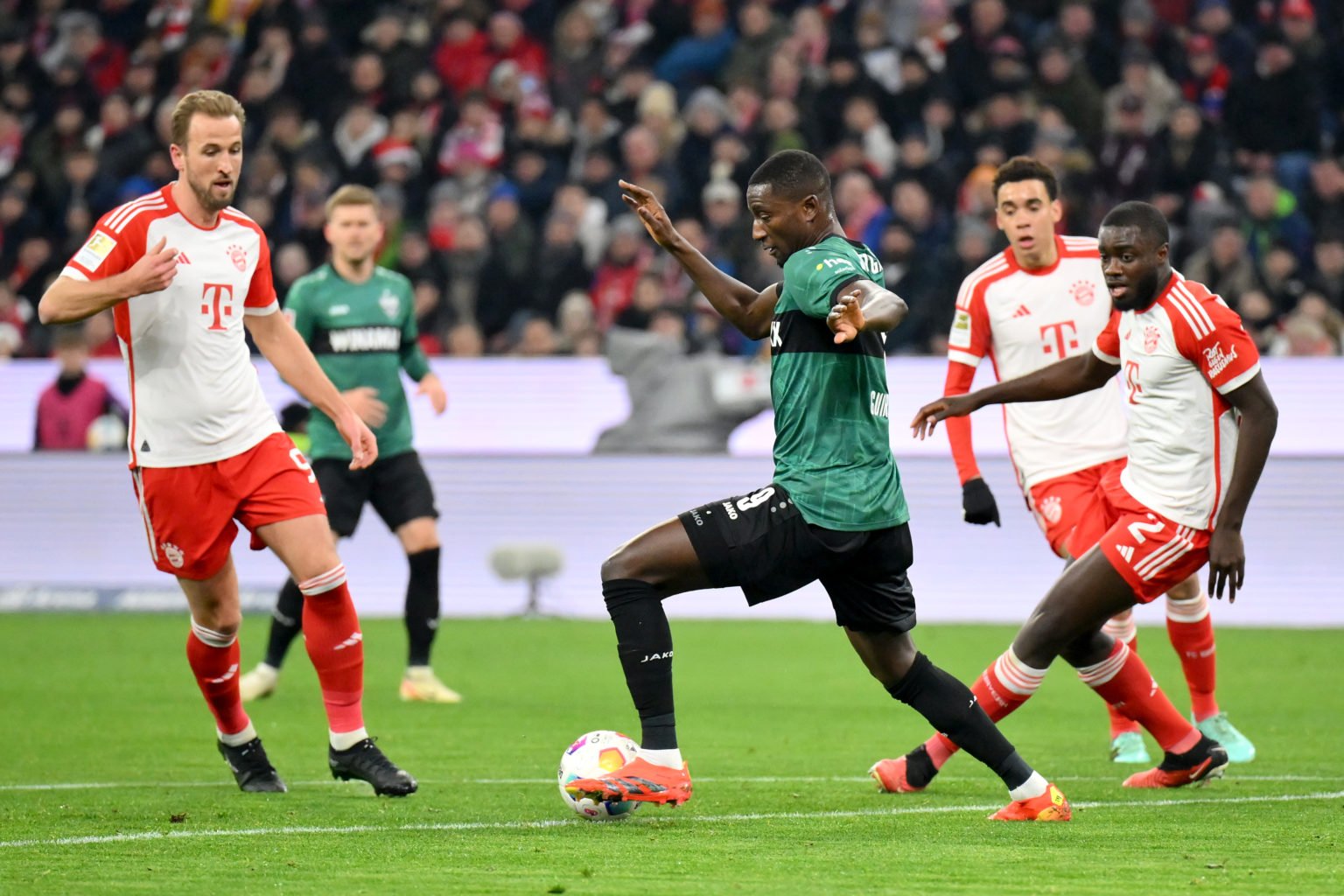 Harry Kane and Dayot Upamecano of Bayern Munich battle for possession with Sehrou Guirassy of VfB Stuttgart during the Bundesliga match between FC ...