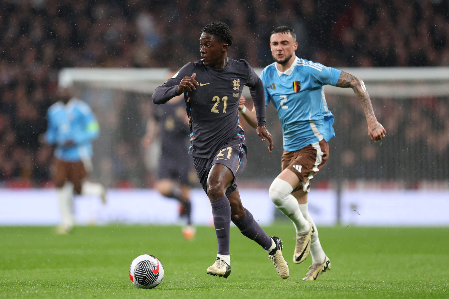 Kobbie Mainoo of England runs with the ball whilst under pressure from Zeno Debast of Belgium during the international friendly match between Engla...