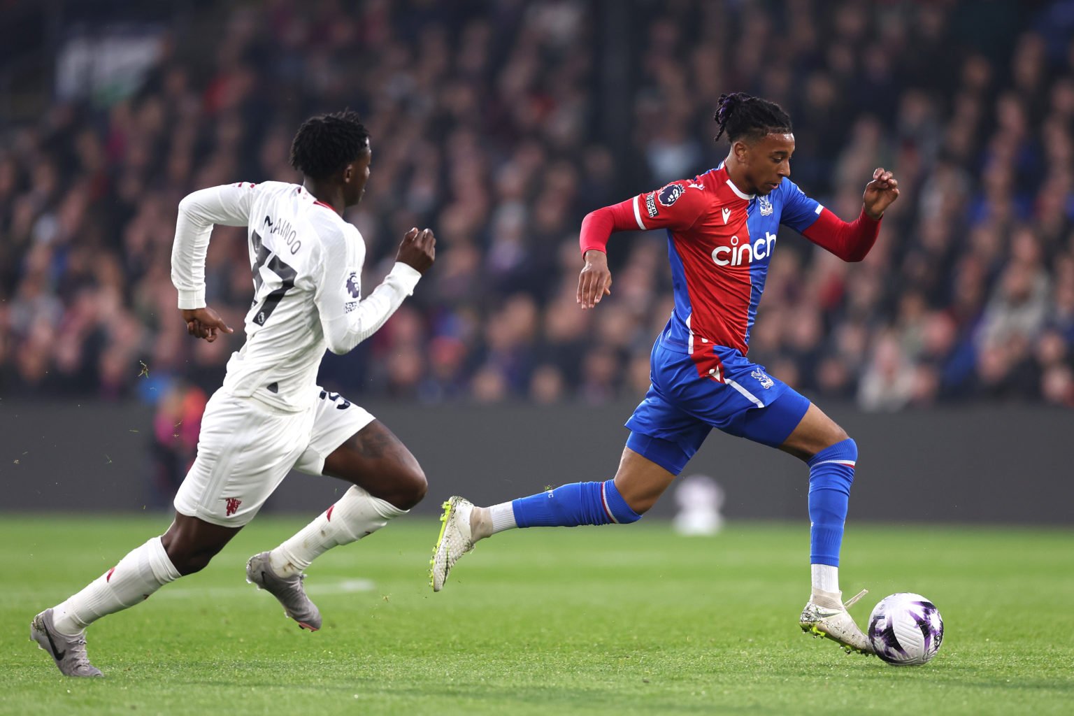 Michael Olise of Crystal Palace runs past Kobbe Mainoo of Manchester United during the Premier League match between Crystal Palace and Manchester U...