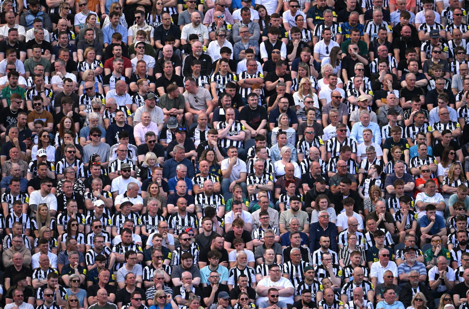 Newcastle United fans wearing black and white shirts support their team in the Leazes End during the Premier League match between Newcastle United ...