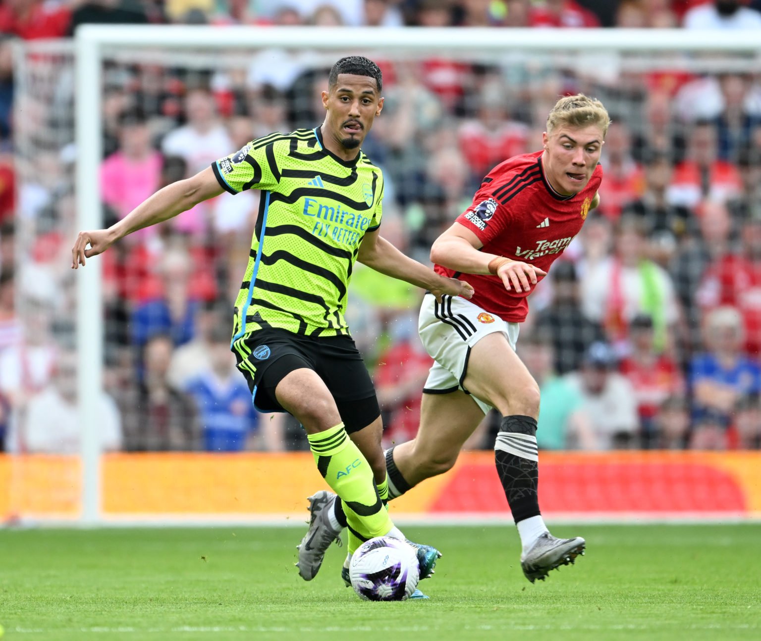 William Saliba of Arsenal runs with the ball whilst under pressure from Rasmus Hojlund of Manchester United during the Premier League match between...