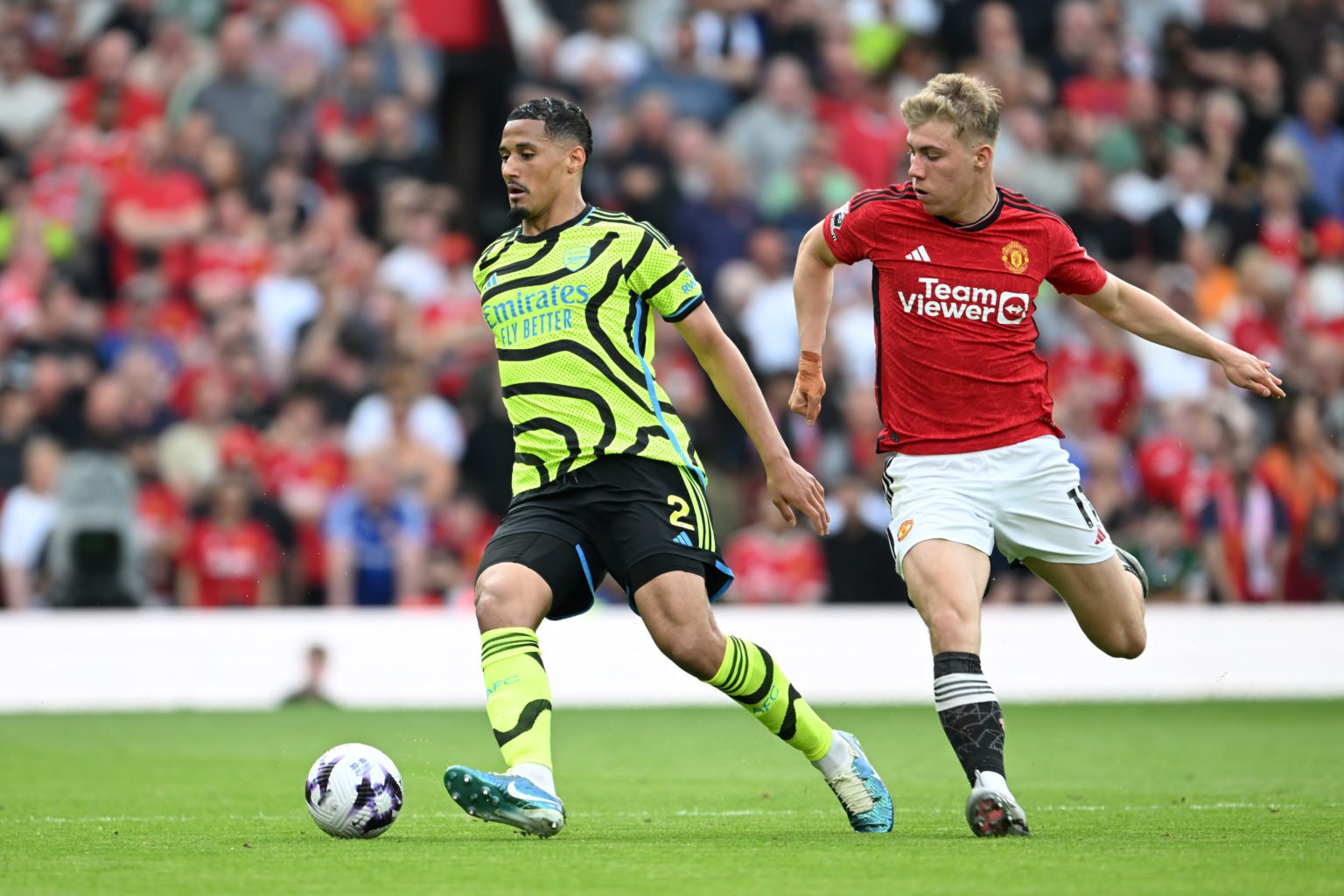 William Saliba of Arsenal runs with the ball whilst under pressure from Rasmus Hojlund of Manchester United during the Premier League match between...