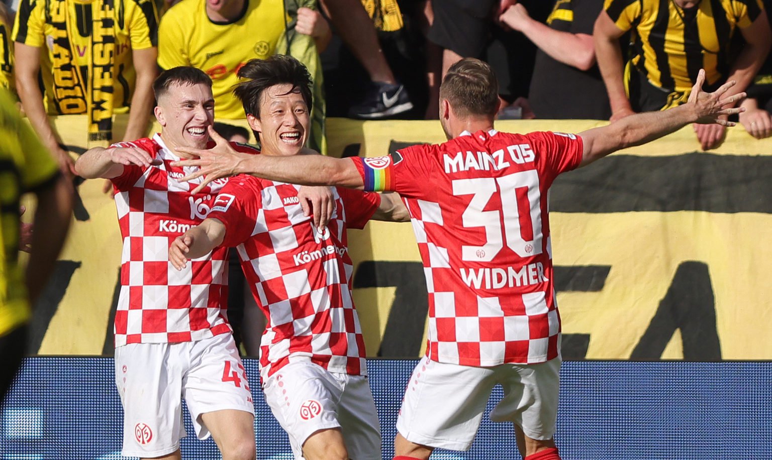 Jae-sung Lee of 1. FSV Mainz 05 (C) celebrates with teammates Brajan Gruda of 1. FSV Mainz 05 (L) and Silvan Widmer of 1. FSV Mainz 05 after scorin...