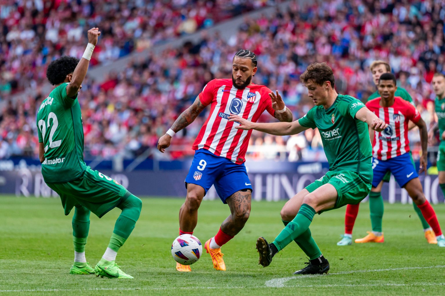 Memphis Depay of Atletico Madrid is in action with the ball against Johan Mojica and Jorge Herrando of CA Osasuna during the La Liga EA Sports 2023...