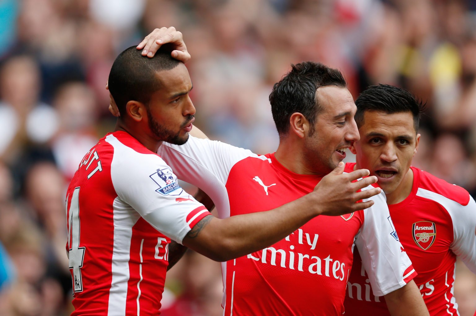 Theo Walcott (L) of Arsenal scores his team's first goal with his team mates Santi Cazorla (C) and Alexis Sanchez (R)  during the Barclays Premier ...