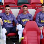 Giovani Lo Celso, Pedro Porro and Ben Davies of Tottenham Hotspur look on from the substitute bench prior to the Premier League match between Brent...