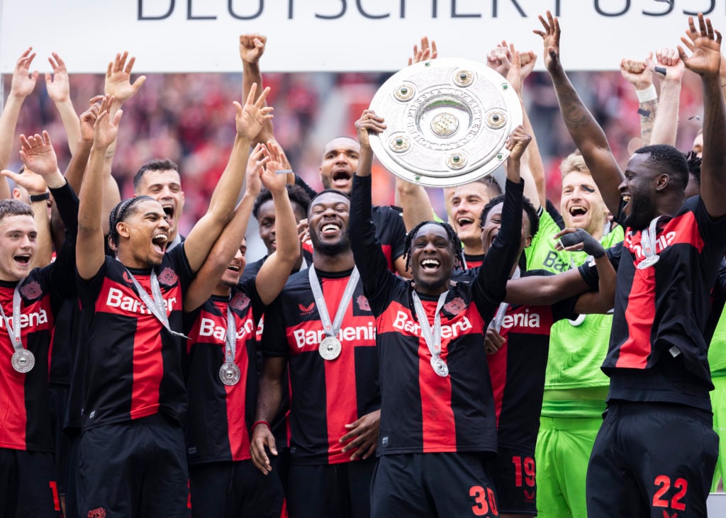 Jeremie Frimpong of Leverkusen celebrates the winning of championship trophy with Florian Wirtz of Leverkusen (L), Nathan Tella of Leverkusen (3.L)...